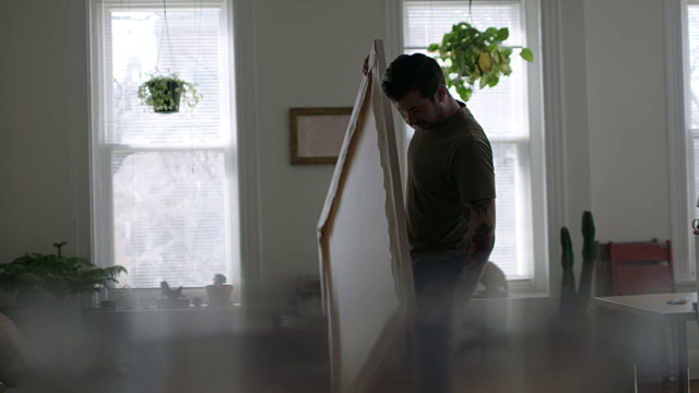 年轻的DIY艺术家WS SLO在现代公寓里组装大的空白画布。视频素材