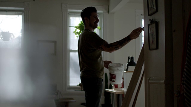 WS SLO MO。微笑的艺术家在公寓工作室的画布绘画。视频素材