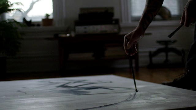年轻艺术家莫斯洛倚在公寓地板上的画布上，用纤长的笔触作画。视频素材