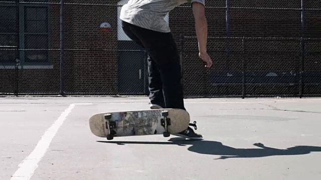一名20多岁的年轻人在纽约布鲁克林的街道上玩滑板时摔倒了——慢镜头视频下载