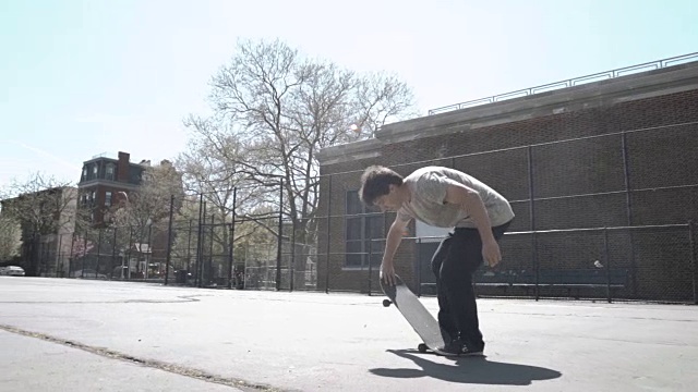 一名20多岁的年轻人在纽约布鲁克林的街道上玩滑板时摔倒了——慢镜头视频下载