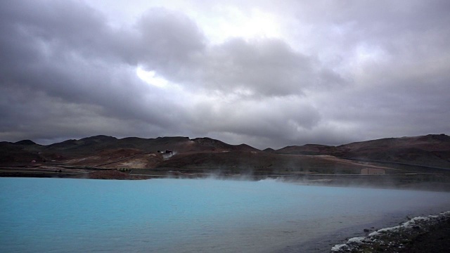 冰岛，一个梦幻般的蓝色湖泊，背景是一个冒着热气的水力发电站视频下载