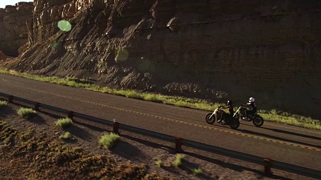 两个人骑着摩托车绕着公路弯道，慢镜头视频素材