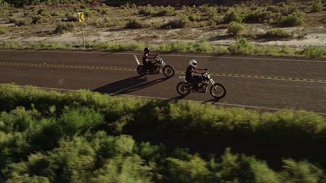 两名男子在沙漠高速公路上驾驶摩托车，鸟瞰图视频下载