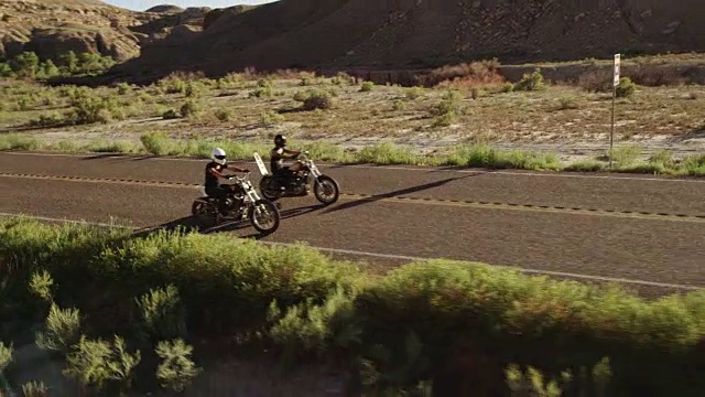 慢镜头，男人和女人在沙漠公路上骑摩托车视频素材