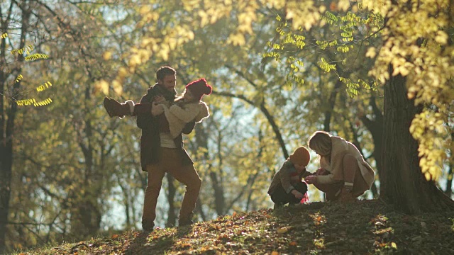 快乐的父母和他们的孩子在森林里享受秋天的一天。视频素材