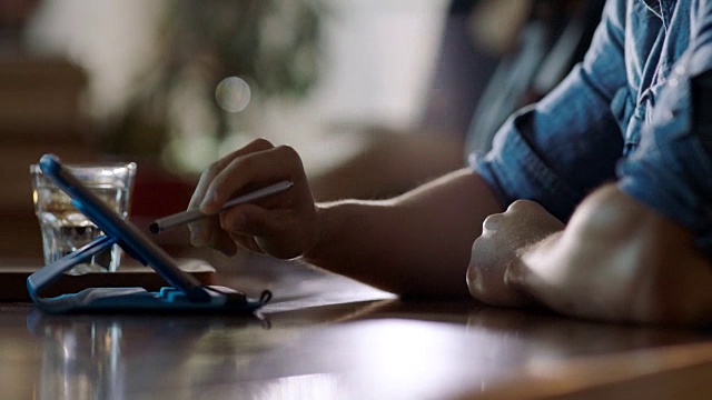 铜。在现代咖啡店里，年轻人在平板电脑上移动触控笔。视频素材