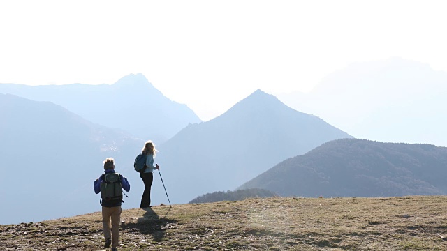 徒步旅行的夫妇穿越雪山之上的山脊视频素材