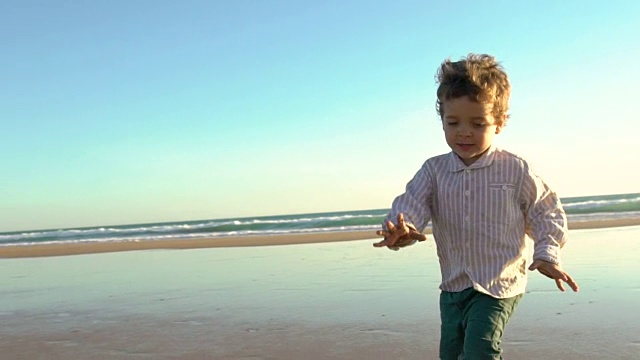 一个可爱的孩子在沙滩上享受阳光的慢动作视频素材