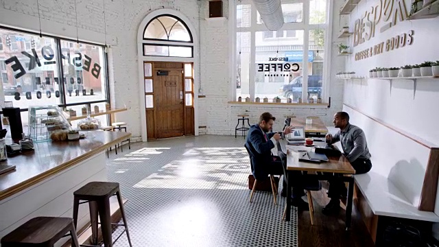 WS。当商业伙伴在市中心的一家现代咖啡店里讨论文书工作和喝咖啡时，相机吊了起来。视频素材