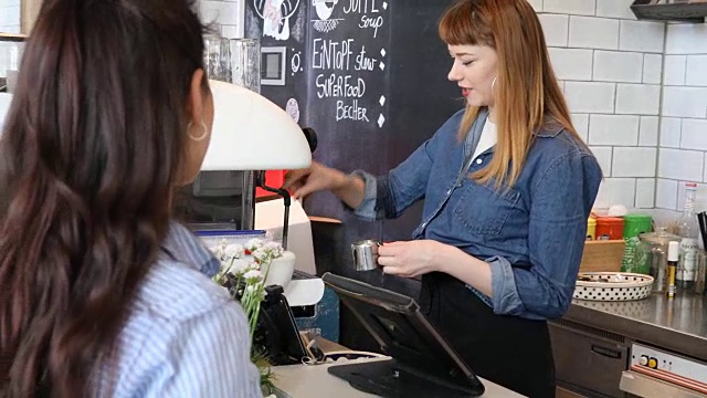 年轻女咖啡师在咖啡馆与顾客交谈视频素材