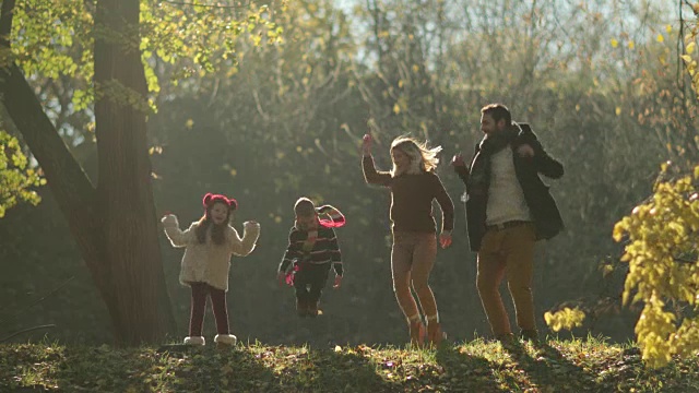 欢乐的一家人在公园里跳跃，在秋天里玩耍。视频素材