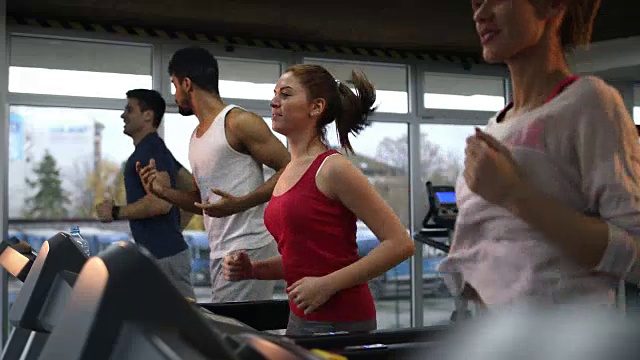 一群年轻运动员在健身俱乐部的跑步机上跑步。视频素材