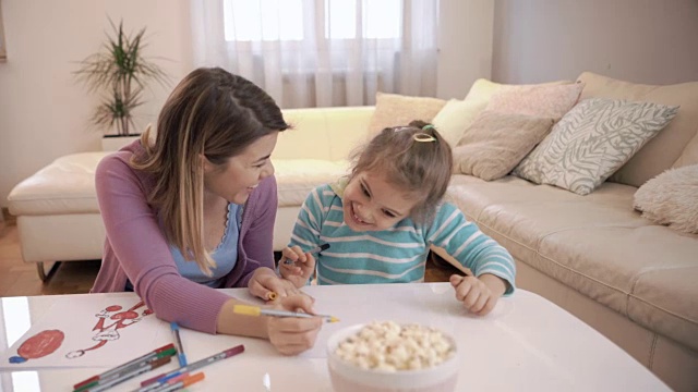 快乐的母亲和她的女儿有乐趣，而涂色在家。视频素材