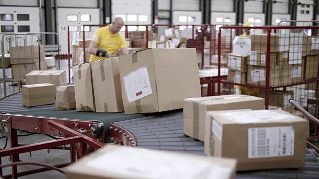 包裹通过传送带运送给工人，工人将包裹从传送带上取下并堆叠起来视频素材