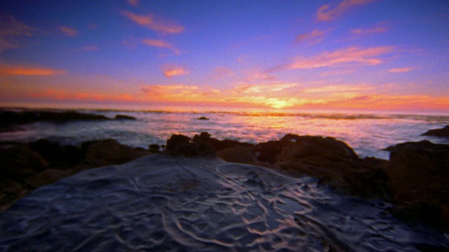 日落(或日出)时从地面岩石到海洋的低视角视频下载