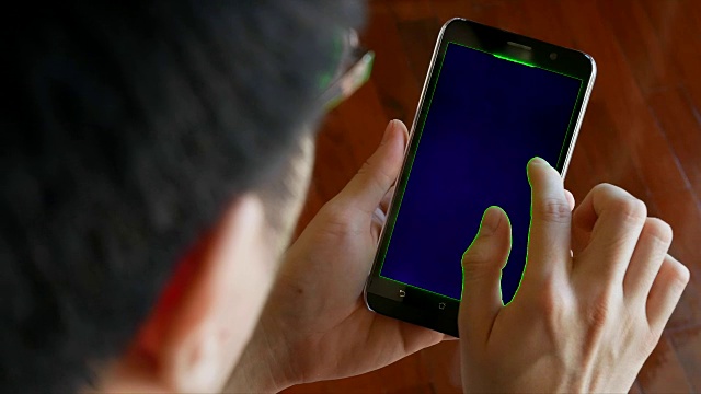 男人用手机与绿色屏幕为色度键-室内场景视频素材
