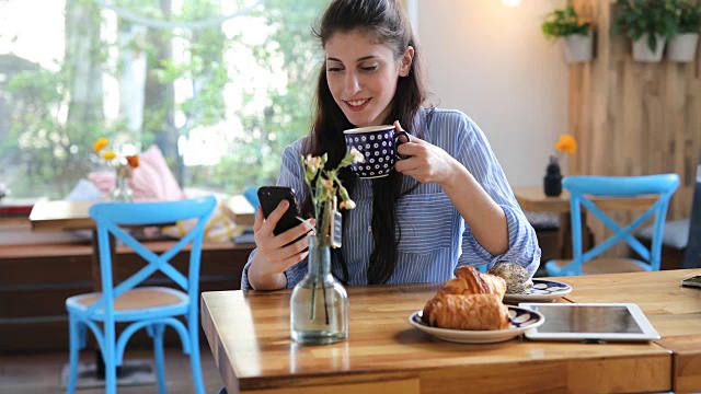 微笑的女性顾客在咖啡馆使用手机视频素材