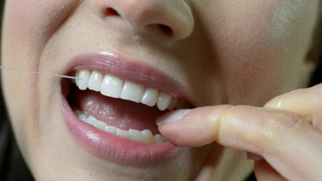 女人用牙线清洁洁白牙齿的特写视频素材