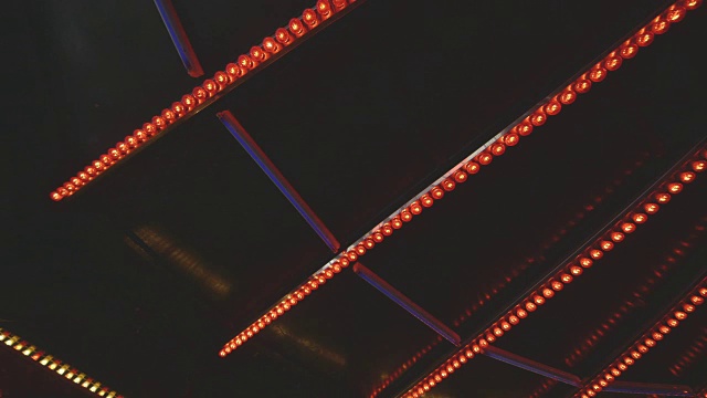 近景，静态拍摄的红色灯泡在一个游乐场的屋顶上不断闪烁的模式，英国。视频素材