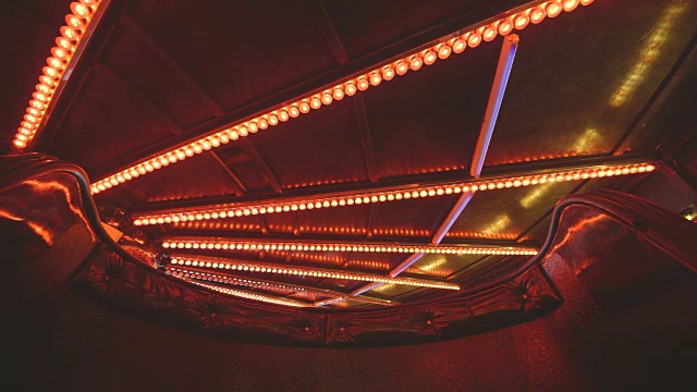低角度序列拍摄于一辆华尔兹车的脚下，扇形的红色灯泡在英国的一个集市上闪烁。视频素材