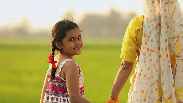 后视图的一个成年妇女走在她的女儿在农场，哈里亚纳，印度视频素材