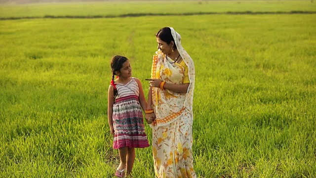 一名成年妇女和她的女儿在印度哈里亚纳邦的农场里散步视频素材