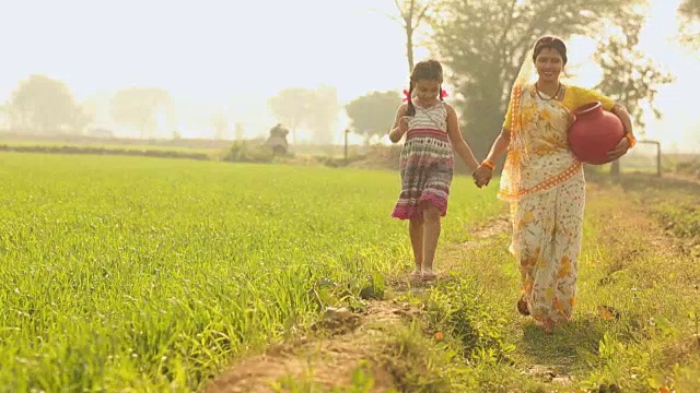 一名成年妇女和她的女儿在印度哈里亚纳邦的农场里散步视频素材