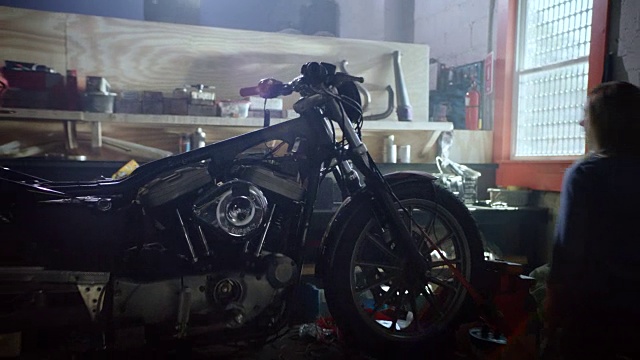 镜头跟随年轻的女机械师走进车库，走上修理台上的摩托车。视频下载