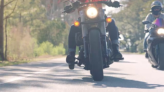 三名女子骑着摩托车在阳光大道的弯道上飞驰。视频下载