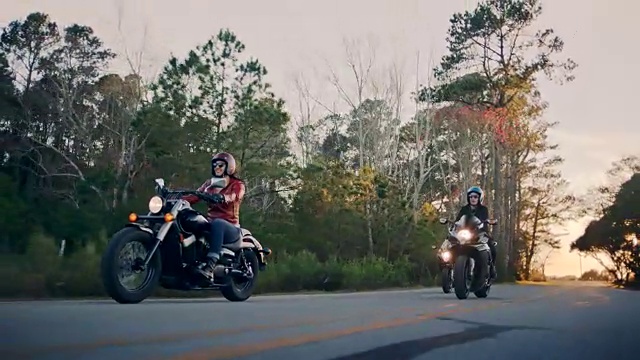 日落时分，三个女性朋友骑着摩托车在沿海公路上行驶。视频素材
