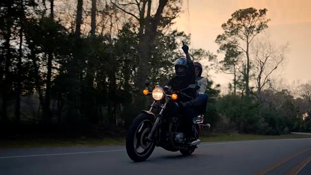 SLO MO。女孩在后面的摩托车点前面和摩托车司机指向天空在公路旅行冒险。视频素材