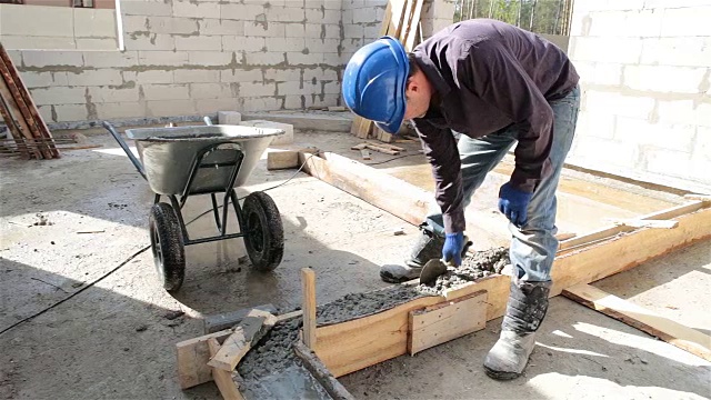 工人用泥铲将混凝土放入模板中。视频下载
