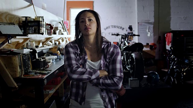 肖像。强悍的女机修工在摩托车修理厂清洗双手和交叉双臂。视频素材