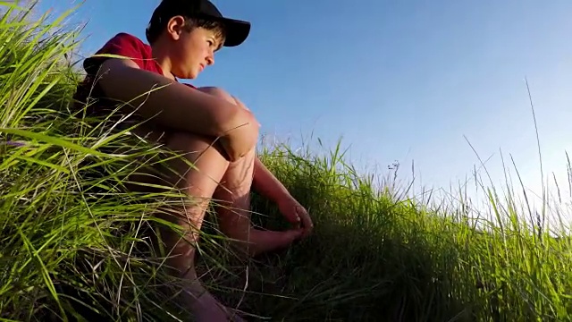那个男孩赤着脚坐在草地上视频下载