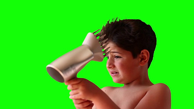 男孩在绿色屏幕上用吹风机吹头发视频下载