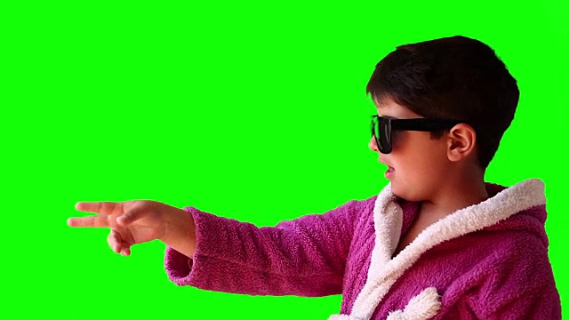 一个穿着浴袍、戴着太阳镜的男孩在绿色屏幕上做鬼脸视频下载