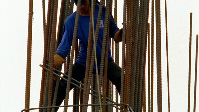 一组建筑工人/ 2名工人站在不稳定的钢筋上视频下载