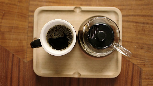 头顶电镀镜头，手把杯子放在托盘上，从咖啡壶倒咖啡在咖啡店。视频素材
