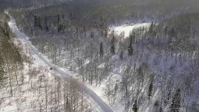 无人机拍摄的冬天森林里的雪道上的汽车比赛视频素材