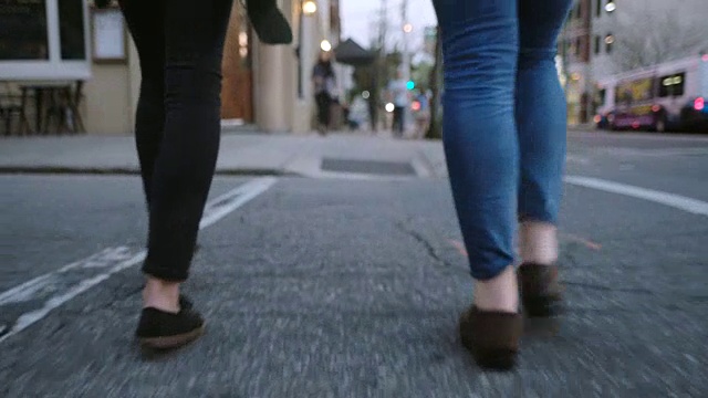 两个年轻女子在人行横道穿过市中心街道。视频下载