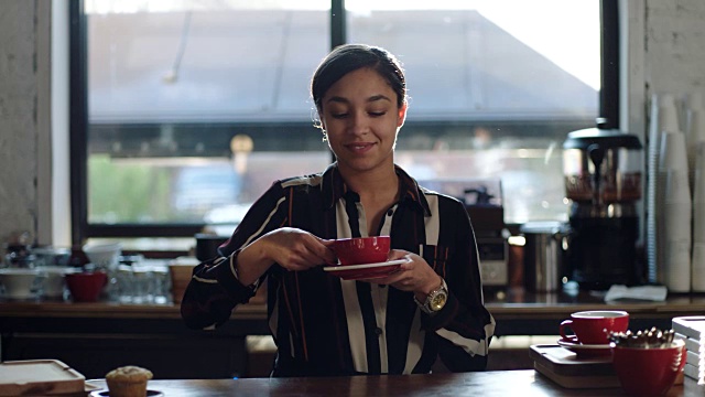 MO SLO女士:当地咖啡馆的咖啡师在柜台后拿起杯子啜饮咖啡的肖像。视频下载