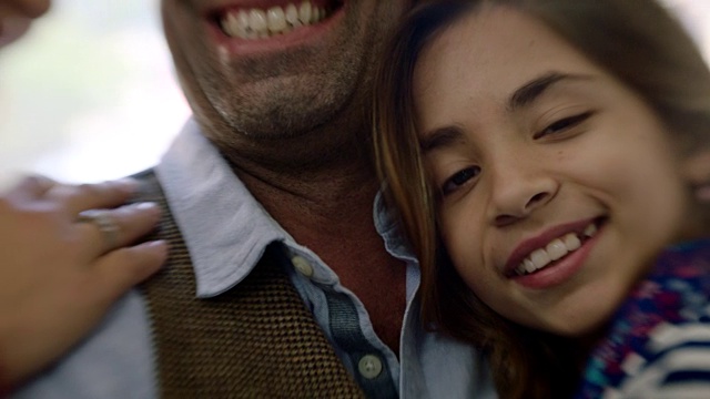 小女孩靠在父亲身上，对着镜头微笑眨眼。视频素材