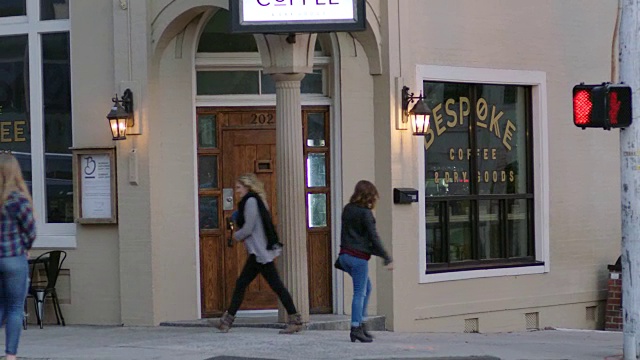 两个女孩走到市中心街角的当地咖啡店。视频素材