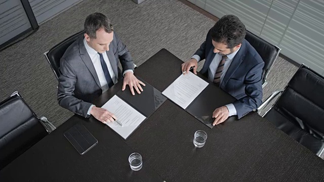 LD就在桌子的正上方，两个商人在这里签合同并握手视频素材