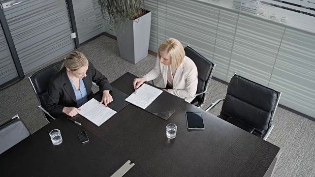 CS:两个白人女商人坐在会议室里，浏览着桌上的文件视频素材