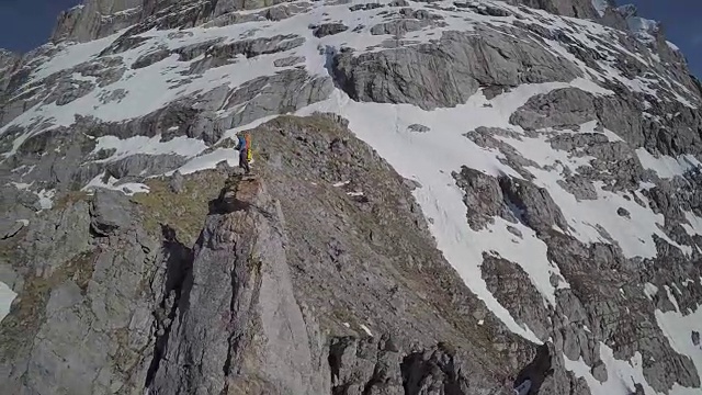 速度无人机视角的登山者攀登一个高山峰的顶峰视频素材