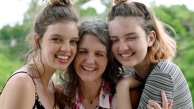 母亲和两个女儿对着镜头微笑的肖像。视频素材