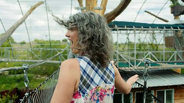 兴奋的妈妈带着女儿跑过绳索吊桥，回头一看，笑了。视频下载