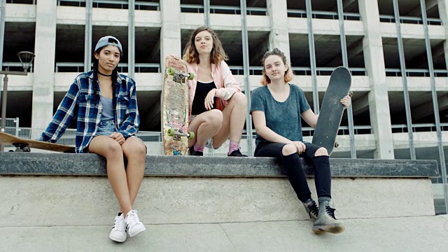 WS SLO MO.三个女孩的肖像与滑板盯着相机在滑板公园的混凝土墙信心。视频下载